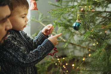 Little boy decorating Christmas tree at home - ANAF02665