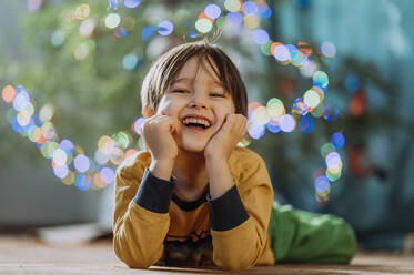 Happy boy lying on floor at home - ANAF02674