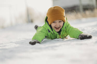 Fröhlicher Junge im Schnee liegend - ANAF02678