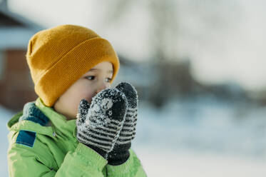 Junge mit Fäustling und wärmenden Händen im Winter - ANAF02679
