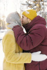 Mann küsst Frau im Winter an einem sonnigen Tag - SANF00176