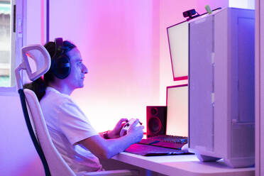 Gamer, der ein Gamepad benutzt und ein Videospiel an einer Spielstation spielt - DAMF01290