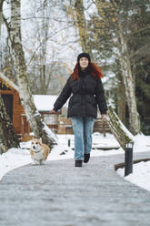 Junge Frau mit Corgi-Hund auf dem Gehweg - OLRF00123