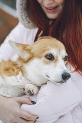 Young woman holding Corgi dog in arms - OLRF00127