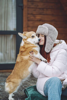 Young woman holding Corgi dog on porch - OLRF00131