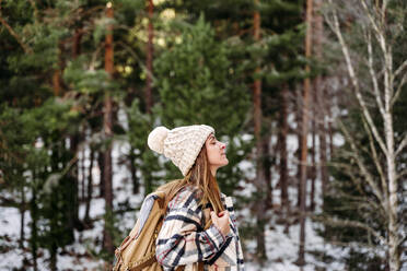 Woman with eyes closed standing in front of trees - EBBF08299