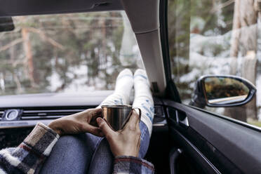 Frau hält Kaffeetasse und sitzt im Auto - EBBF08304