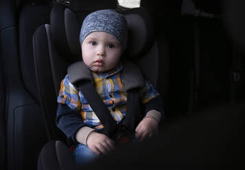 Niedlicher Junge mit Sicherheitsgurt und im Auto sitzend - NJAF00734