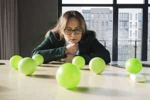 Nachdenkliche Geschäftsfrau betrachtet Bälle auf dem Tisch im Büro - OSF02366