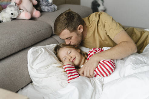 Father kissing daughter sleeping on bed at home - SEAF02175