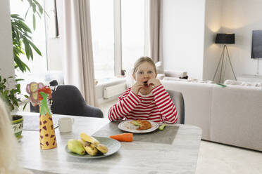 Girl having breakfast at dining table in living room at home - SEAF02205