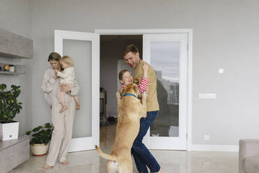 Mädchen und Hund spielen mit Vater in der Nähe der Tür zu Hause - SEAF02209