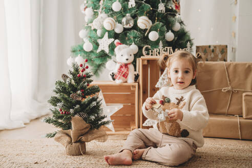 Lächelndes Mädchen spielt mit Weihnachtsdekoration zu Hause - EBBF08325
