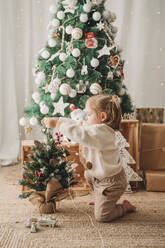 Mädchen schmückt kleinen Weihnachtsbaum zu Hause - EBBF08327
