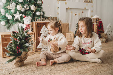 Mädchen spielen und schmücken einen kleinen Weihnachtsbaum zu Hause - EBBF08330