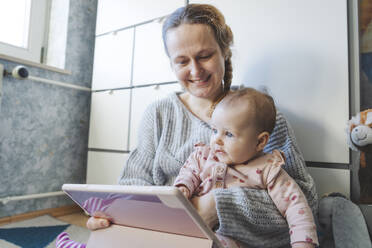 Cute baby girl with mother using tablet PC at home - IHF01875