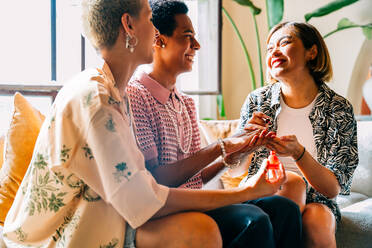 Group of friends bonding at home, LGBTQ and diversity concepts - Homosexual couple and fluid gender non binary young man with cross dressing clothing style having fun in the apartment, LGBT people concepts - DMDF09405