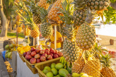 View of pineapples and apples on fruit stall in Grand Bay at golden hour, Mauritius, Indian Ocean, Africa - RHPLF31610