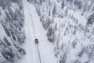 Luftaufnahme eines Autos, das den mit Schnee bedeckten borealen Wald durchquert, Akaslompolo, Finnisch Lappland, Finnland, Skandinavien, Europa - RHPLF31916