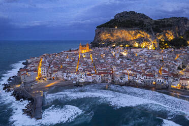 Das beleuchtete Fischerdorf Cefalu mit dem Felsen über der Altstadt von der Drohne aus gesehen in der Abenddämmerung, Cefalu, Provinz Palermo, Tyrrhenisches Meer, Sizilien, Italien, Mittelmeer, Europa - RHPLF31939