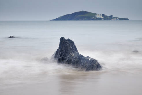 Blick in der Abenddämmerung auf die Felsen am Strand von Bantham, mit Blick auf Burgh Island und das dazugehörige Hotel, an der Südküste von Devon, England, Vereinigtes Königreich, Europa - RHPLF32128