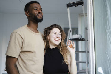 Happy couple standing near ladder in new home - DANF00033