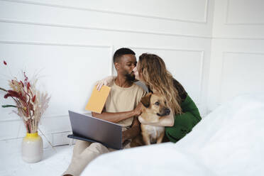 Couple kissing near dog at home - DANF00039