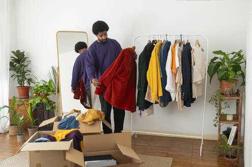 Young man decluttering clothes at home - VRAF00269