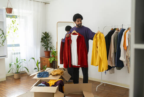 Man organizing and decluttering clothes at home - VRAF00272