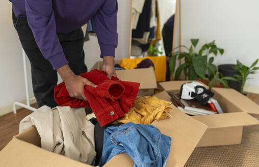 Man decluttering clothes at home - VRAF00276