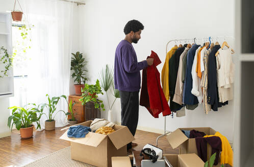 Man decluttering clothes for recycling at home - VRAF00278