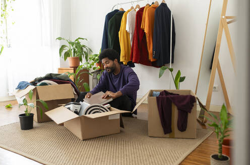 Man organizing clothes and objects in cardboard boxes - VRAF00283