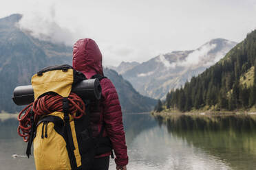 Young woman with backpack standing in front of lake Vilsalpsee and mountains at Tyrol, Austria - UUF31086