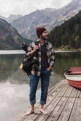 Junger Mann steht auf einem Steg am Vilsalpsee in Tirol, Österreich - UUF31095