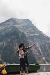 Mann gestikuliert mit Frau, die vor einem Berg in Tirol, Österreich, steht - UUF31100