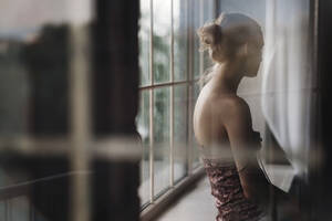 Nachdenkliche Frau sitzt zu Hause auf der Fensterbank - AZF00594