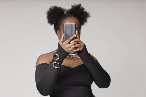 Junge Frau nimmt Selfie gegen grauen Hintergrund - KPEF00584