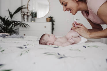 Glückliche Mutter spielt mit Baby Mädchen auf dem Bett zu Hause - EBBF08342