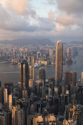 Victoria harbor near buildings in Hong Kong city under cloudy sky at sunset - MMPF01166