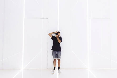 Mann beim Fotografieren mit Kamera in modernem Korridor - MMPF01220