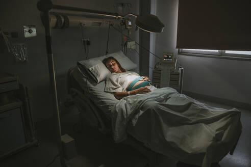 Schwangere Frau schläft auf einem Bett in der Nähe von Geräten im Kreißsaal eines Krankenhauses - EBBF08346