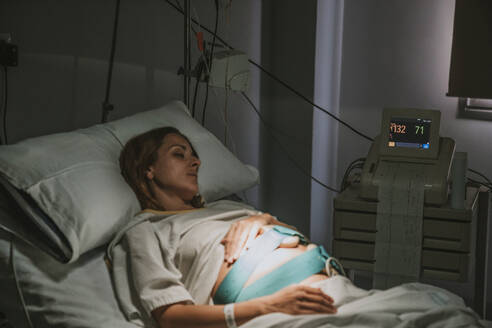 Pregnant woman resting on hospital bed in delivery room - EBBF08347