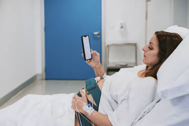 Schwangere Frau benutzt Smartphone im Krankenhauszimmer - EBBF08350