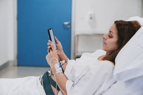 Pregnant woman using mobile phone in delivery room - EBBF08351
