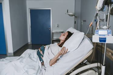Schwangere Frau mit Schmerzen auf dem Bett im Kreißsaal liegend - EBBF08354