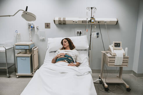 Pregnant woman lying on bed in delivery room - EBBF08368