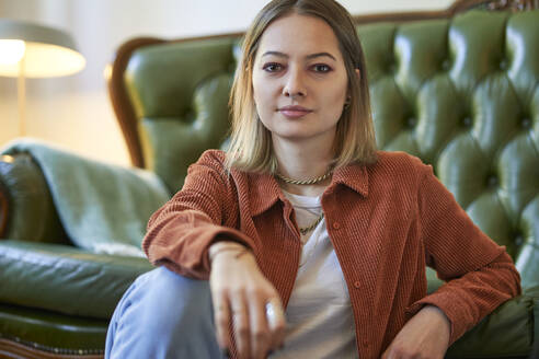 Young beautiful woman sitting near sofa at home - SUF00716