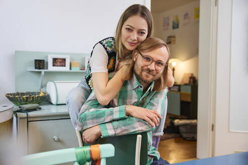 Smiling man and woman sitting together at home - SUF00722