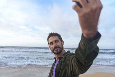 Mann nimmt Selfie durch Smartphone vor dem Meer am Strand - JOSEF23135