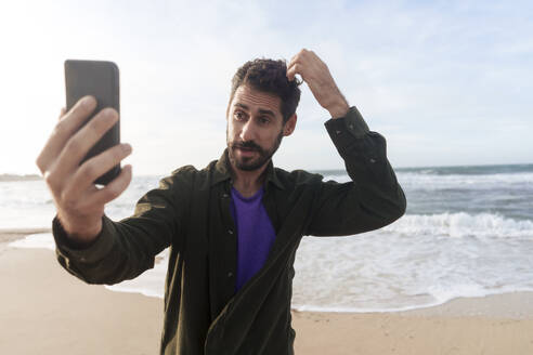 Mann nimmt Selfie durch Smartphone am Strand an einem sonnigen Tag - JOSEF23153